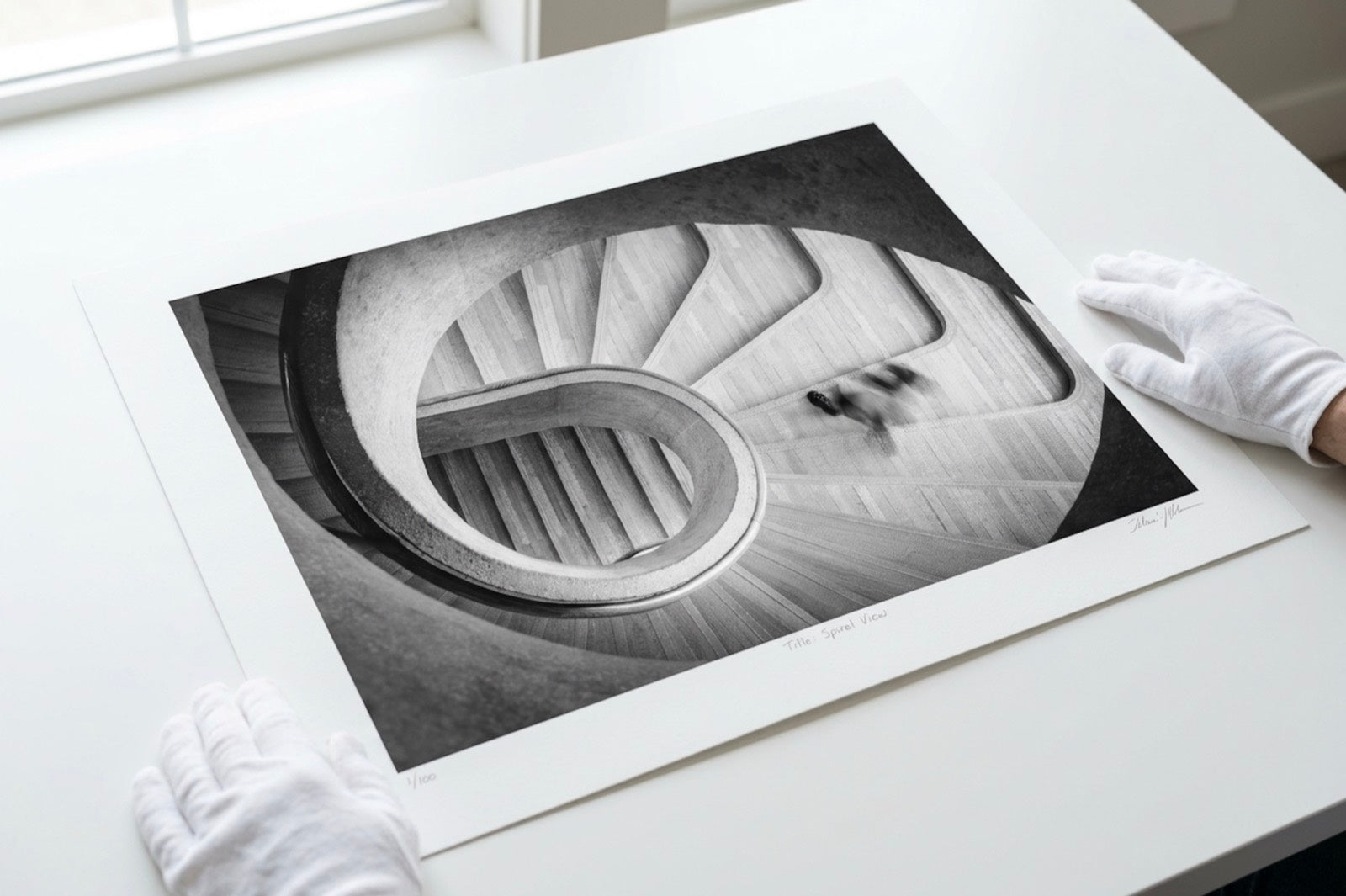 A fine art print handled by its margins with cotton gloves